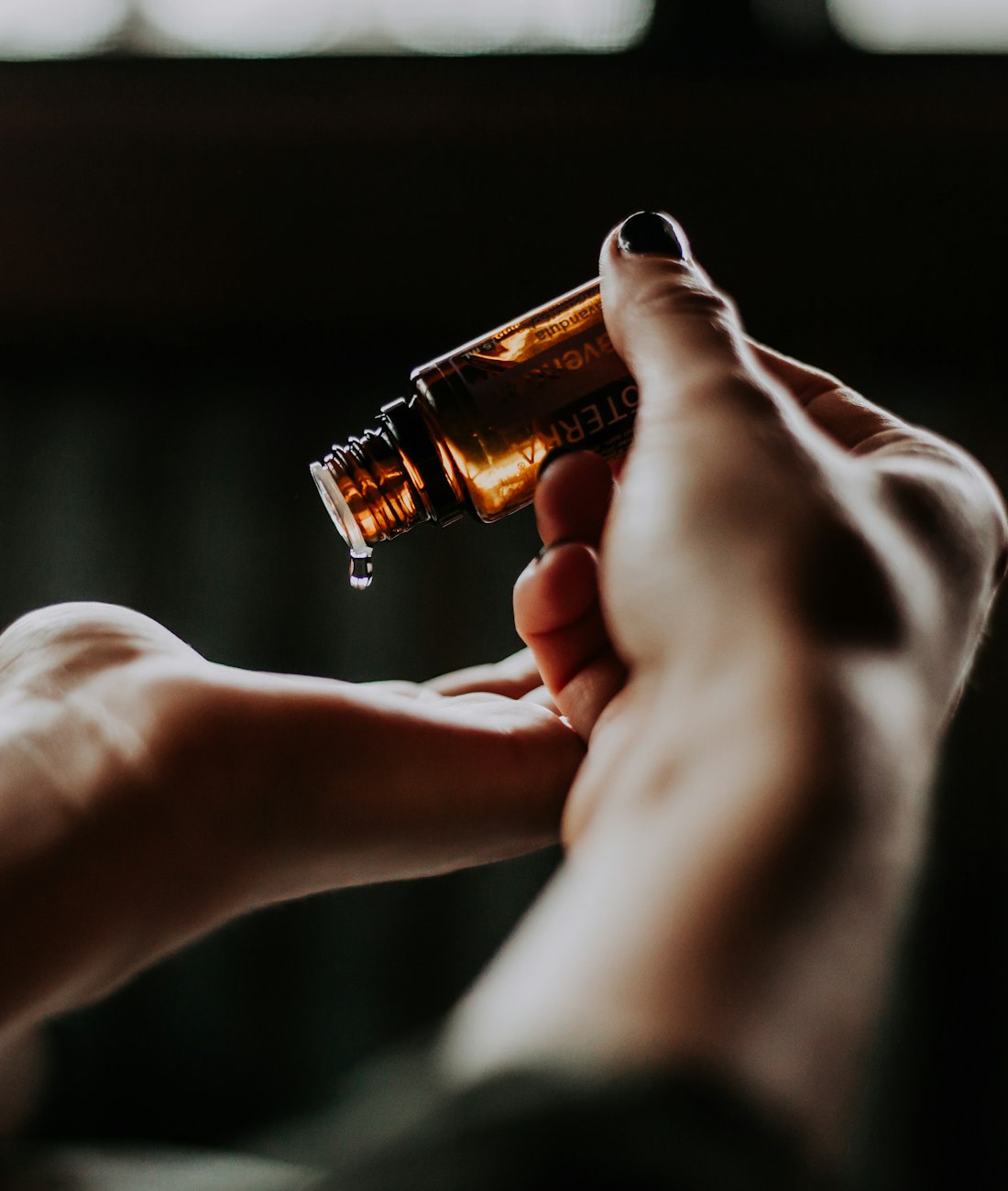 Hands holding an amber essential oil bottle