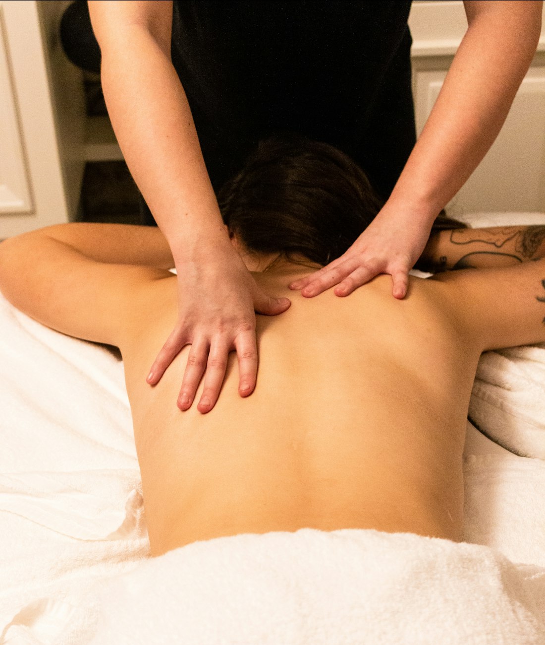Client relaxing face-down while a therapist massages their shoulders